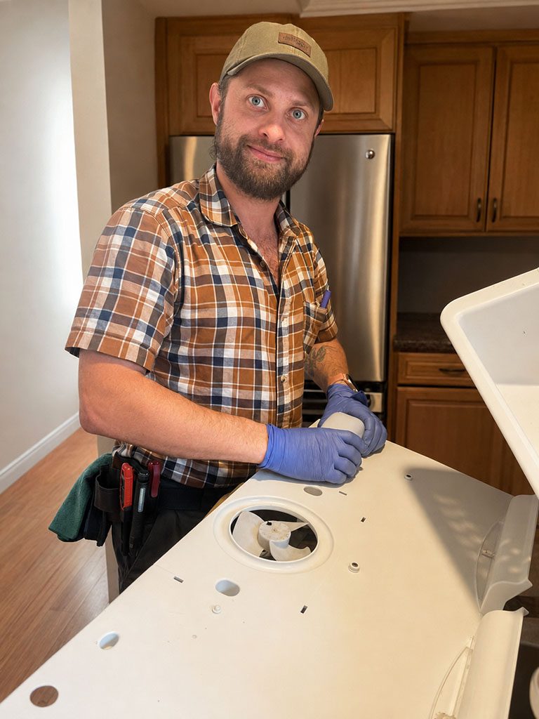 Nikita Vorontsov, owner of Appliance Magician, servicing an appliance in a customer's kitchen